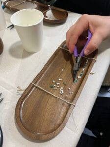 Gros plan sur la création d’un bracelet avec pince, perles et support en bois à Toulouse.