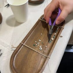 Gros plan sur la création d’un bracelet avec pince, perles et support en bois à Toulouse.