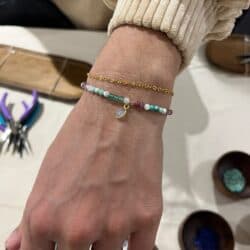 Poignet orné de bracelets dorés et d’un bijou coloré, fabriqué pendant l’atelier.